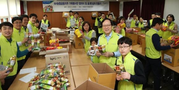 ▲NH농협금융 김용환 회장과 가족봉사단원들이 효(孝) 상자 제작 봉사활동을 하고 있다. 사진 가운데 앞에서 두 번째 김용환 회장의 모습. (사진 : NH농협금융지주 제공)