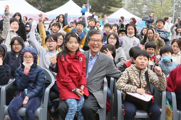 ▲4월 9일(토)에 산업은행 여의도 본점에서 빨간옷을 입은 어린이를 안고 있는 KDB산업은행 이동걸 회장과 4개 결연 복지시설 어린이들이 단체사진을 촬영하였다.