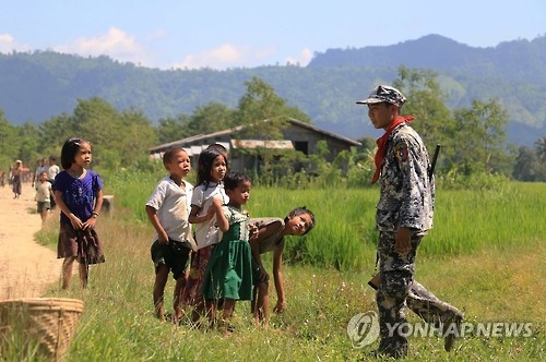지난 21일 미얀마 서부 라카인 주에서 무슬림 무장단체 색출 작전을 진행 중인 미얀마 국경 경찰대 소속 경찰관을 마을 어린이들이 호기심 어린 눈으로 바라보고 있다. [AFP=연합뉴스자료사진]