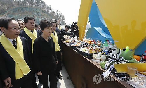 박근혜 대통령이 세월호 1주년을 맞은 16일 오후 전남 진도군 팽목항을 방문, 희생자와 실종자를 위해 마련된 추모 메시지와 음식들이 놓인 단 앞을 지나가고 있다.