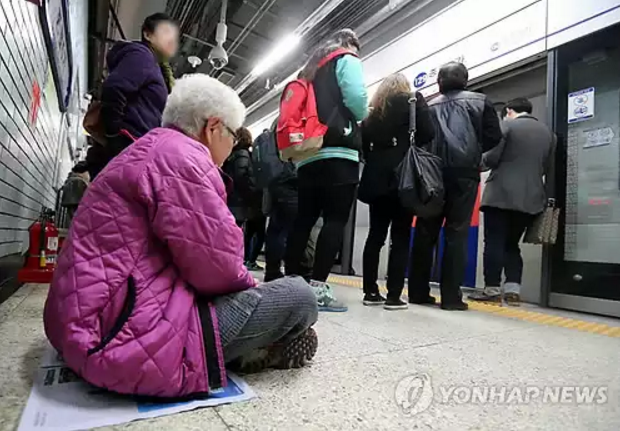 지하철역 바닥에 앉아 있는 한 노인 