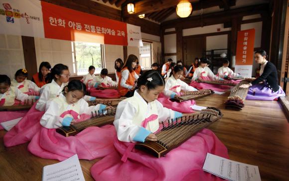 ▲4월 21일, 서울 남산국악당 체험실에서 전통문화예술교육사업인 &lsquo;한화예술더하기&rsquo; 사회공헌 활동에 참석한 한화그룹 임직원 봉사자들과 아동들이 가야금 교육에 참여하고 있다. (사진 : 한화그룹 제공)