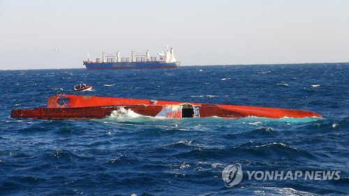 10일 오후 경북 포항 앞바다에서 오징어채낚기 어선이 대형 상선과 충돌해 뒤집히자 출동한 해경이 선원을 구조하고 있다. 뒤집힌 어선 209주영호 뒤로 해경 구조 보트와 상선이 보인다. 2017.1.10 [포항해양경비안전서 제공=연합뉴스]