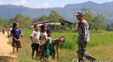 지난 21일 미얀마 서부 라카인 주에서 무슬림 무장단체 색출 작전을 진행 중인 미얀마 국경 경찰대 소속 경찰관을 마을 어린이들이 호기심 어린 눈으로 바라보고 있다. [AFP=연합뉴스자료사진]
