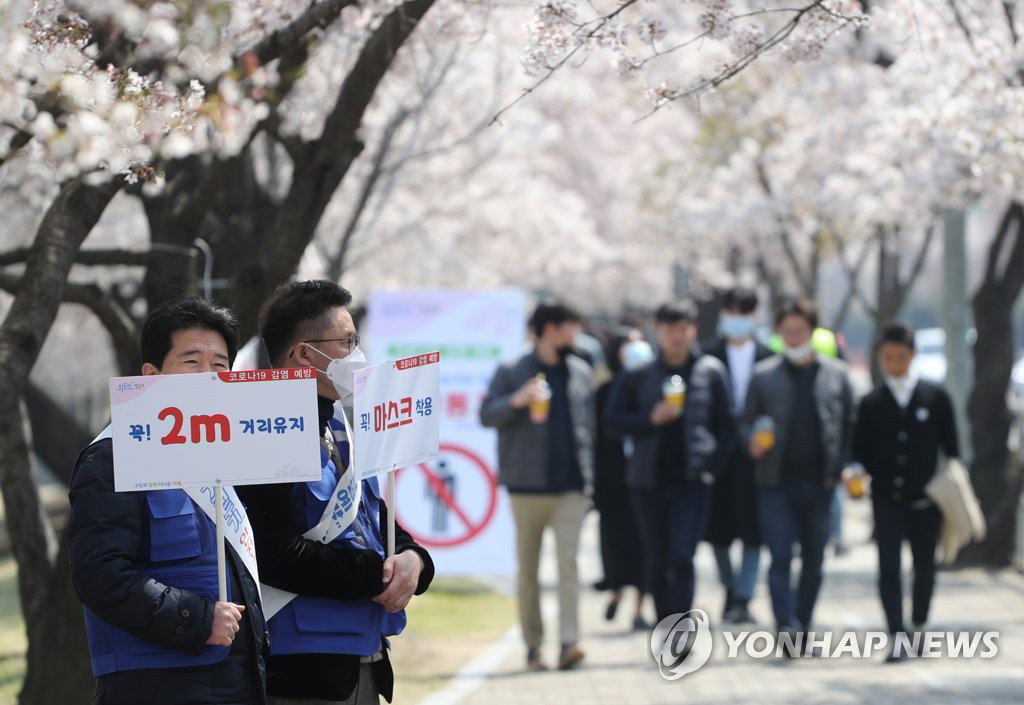 6일 점심시간 여의나루역 인근에서 회사원들이 벚꽃길을 걷고 있다. 영등포구청 직원들이 마스크 착용과 2m 거리두기 팻말을 들고 코로나19 예방 캠페인을 하고있다.