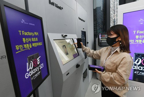 22일 오전 서울 마포구 홍대 T팩토리에서 열린 SK텔레콤 갤럭시S21 무인 개통식을 찾은 고객이 무인 개통 키오스크를 통해 갤럭시S21을 수령하고 있다. 2021.1.22