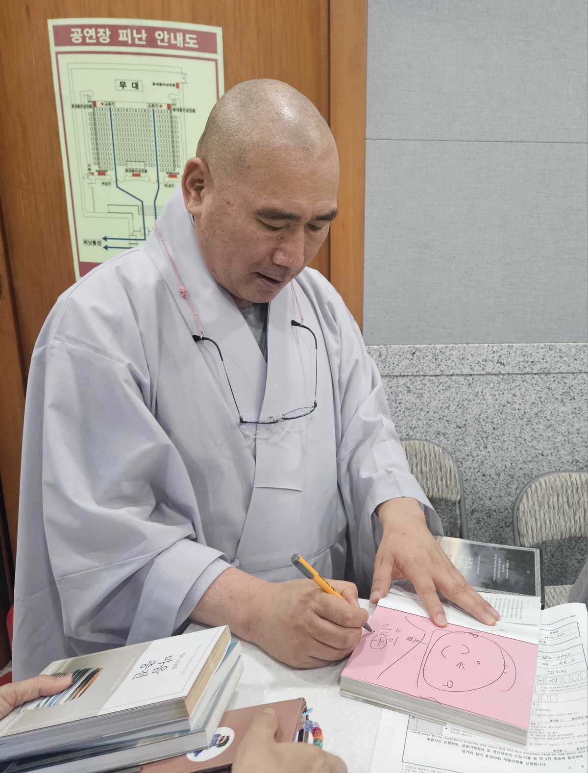 [마가스님이 책에 사인을 하고 있는 모습]
