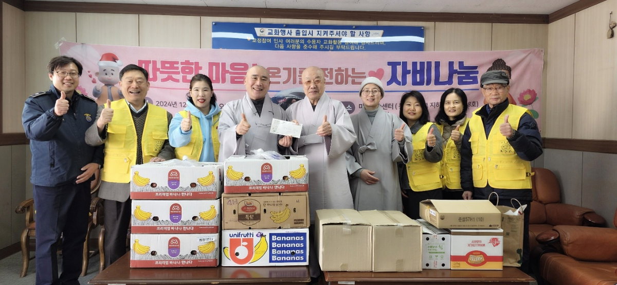 [마가스님이 혜묵스님에게 자비도량참법 책, 과일, 빵, 미고사노트 나눔과 부처님오신날 대중공양비로 100만원을 전달하고 있다]