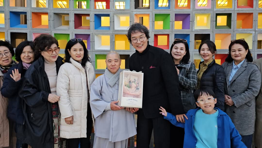 [윤경식 건축가가 인월사 재범 주지스님에게 꽃다발을 선물하고 있다]